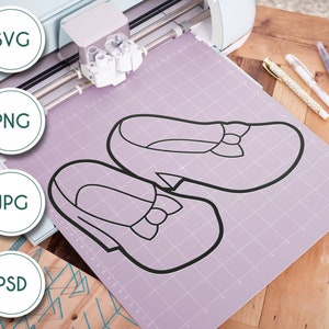 May include: A close-up of a cutting mat with two black outlines of shoes on it. The mat is light purple with a grid pattern. The shoes are simple and have a bow on the top. The mat is on a wooden surface.