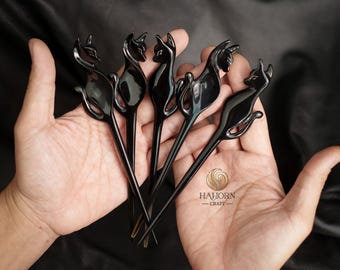 May include: Five black hair sticks with a cat design. The sticks are made of horn and have a polished finish. The cat design is detailed and realistic. The sticks are held in a hand.