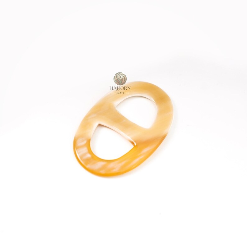 May include: A light-colored, oval-shaped accessory with a rounded design. The accessory has a smooth, polished surface and a cutout in the center. The accessory is made of a light brown material with a gradient of color.
