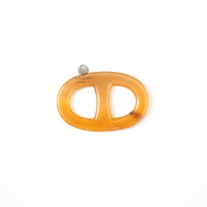 May include: A light amber-colored oval-shaped object with a central vertical bar, resembling a chain link. The object is smooth and appears to be made of a translucent material. The logo "HALIORN - CRAFT" is visible in the upper left corner. The object is set against a white background.