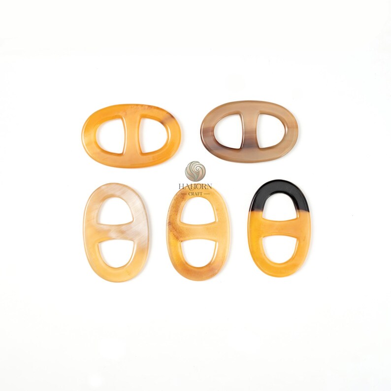 May include: Five oval-shaped decorative clasps in shades of tan, brown, and black. Each clasp features a central bar, creating a double-D shape. The clasps are arranged on a white surface. The brand name "HAJORN CRAFT" is visible.