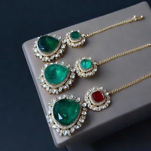 Peut inclure: Quatre colliers pendentifs en or et émeraude en forme de larme avec une chaîne. Les pendentifs sont ornés de petites pierres blanches. Le pendentif du bas est rouge.