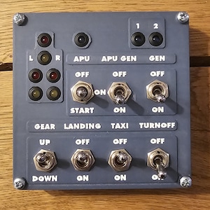 May include: A gray control panel with various switches and lights. The panel has labels for "APU", "APU GEN", "GEN", "GEAR", "LANDING", "TAXI", and "TURNOFF". The switches are labeled "OFF", "ON", "START", "UP", "DOWN", and "ON".