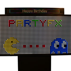 May include: A black LED sign with the words "Happy Birthday" at the top. The main display features the word "PARTY!!!" in colorful pixelated letters, along with Pac-Man and a blue ghost character.