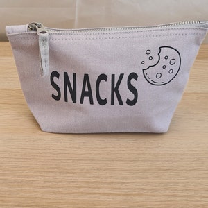 May include: A light grey canvas zippered pouch with a black cookie graphic and the word "SNACKS" printed on the front.