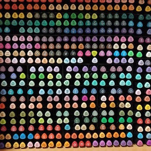 Könnte beinhalten: Eine Sammlung farbenfroher Kunstmarker, die in einem Raster angeordnet sind. Die Marker haben verschiedene Farben, darunter Blau-, Grün-, Rosa- und Gelbtöne. Jeder Marker hat eine nummerierte Spitze. Die Marker sind in einem schwarzen Aufbewahrungsbehälter geordnet.