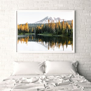 Mountain reflecting in lake with trees in mt rainier national park wall photo framed above bed in bedroom.