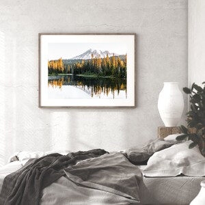 Mountain reflecting in lake with trees in mt rainier national park wall photo framed above bed in bedroom.