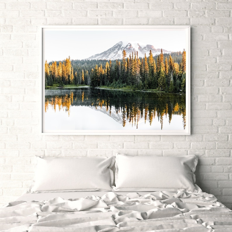 Mountain reflecting in lake with trees in mt rainier national park wall photo framed above bed in bedroom.