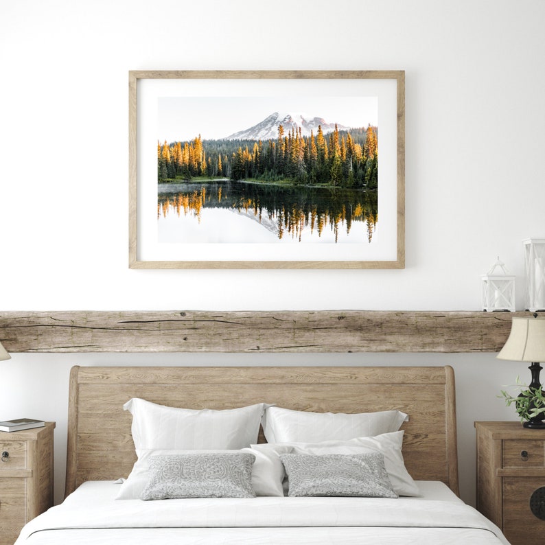 Mountain reflecting in lake with trees in mt rainier national park wall photo framed above bed in bedroom.