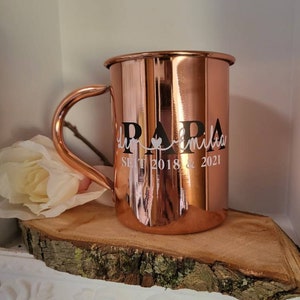 Pode incluir: Uma caneca de cobre com um design em preto e branco que diz "Papa la familia" e "SLT 2018 & 2021".