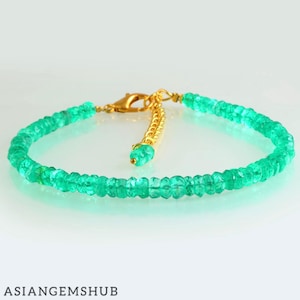 May include: A delicate bracelet featuring small, faceted emerald beads strung together. The bracelet has a gold-colored clasp and a small chain extension with a single emerald bead. The text "ASIANGEMSHUB" is at the bottom.