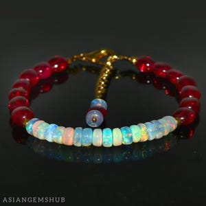 May include: A bracelet with alternating red and iridescent opal beads. The bracelet has a gold clasp and extender chain.