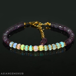 May include: A delicate bracelet featuring a row of iridescent opal beads interspersed with tiny gold beads, set against a backdrop of amethyst beads.