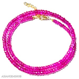 Puede incluir: Un collar de piedras preciosas rosas con un cierre de oro. El collar está hecho de pequeñas cuentas facetadas y está en capas para un look más dramático.