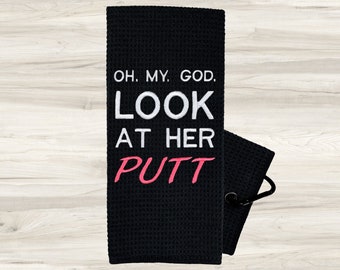 May include: Black golf towel with white text that reads "Oh. My. God. Look at her putt" with the word "putt" in pink.
