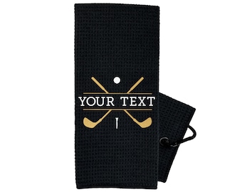 May include: Black golf towel with a white golf club and ball design. The towel has a loop for hanging and the text "YOUR TEXT" in white.