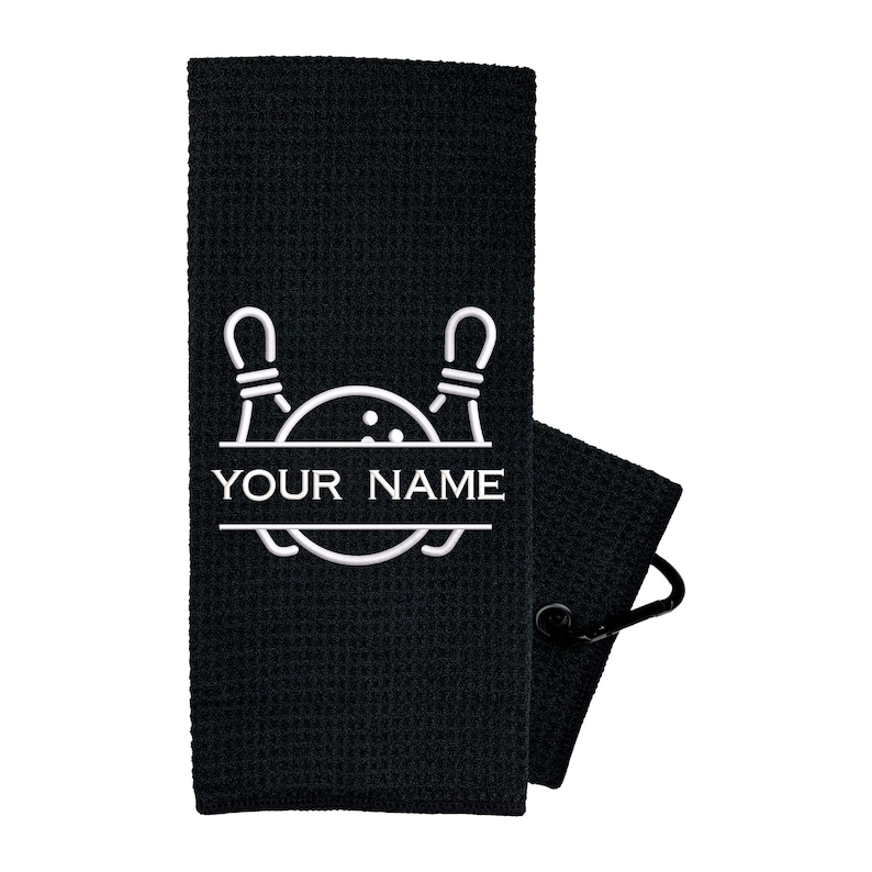 May include: Black waffle weave towel with a white embroidered bowling ball and pins design. The text "YOUR NAME" is centered below the design.