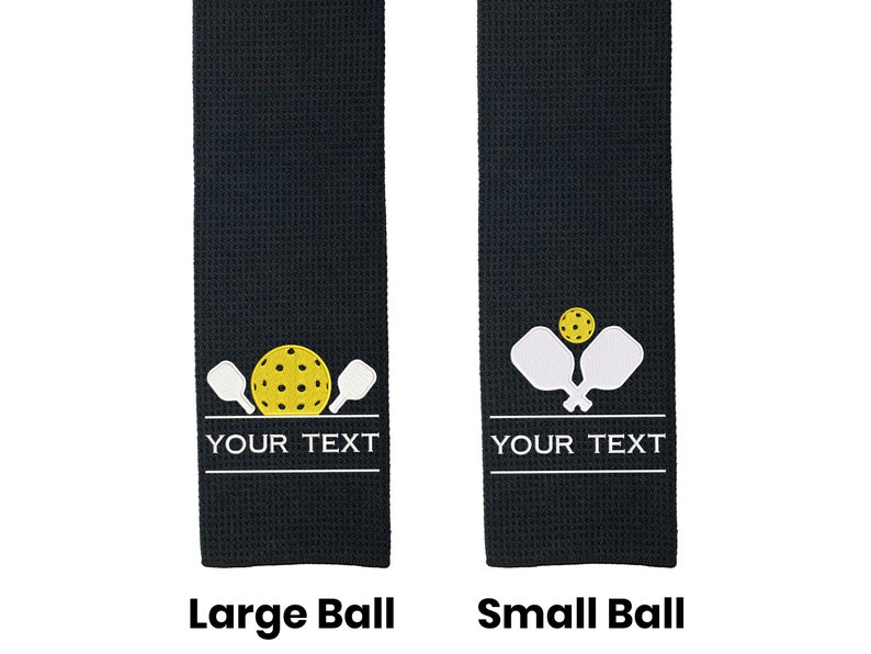 Pode incluir: Duas toalhas de tecido waffle preto com um design branco de duas raquetes de pickleball e uma bola de pickleball amarela. A toalha &agrave; esquerda tem uma bola maior e a toalha &agrave; direita tem uma bola menor. Ambas as toalhas t&ecirc;m o texto "YOUR TEXT" impresso abaixo do design.