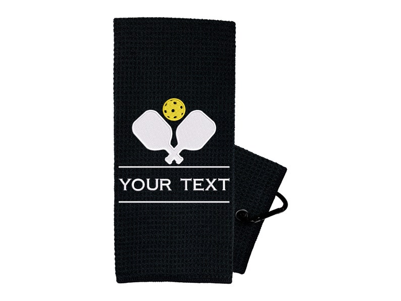 Pode incluir: Toalha de tecido waffle preto com um design branco de raquete e bola de pickleball. A toalha tem um la&ccedil;o para pendurar e diz "YOUR TEXT" em branco.