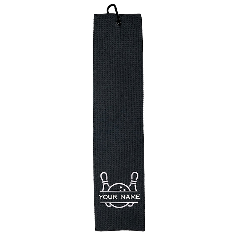 May include: Black golf towel with a white bowling pin and ball design. The towel has a loop for hanging and says "YOUR NAME" in white text.
