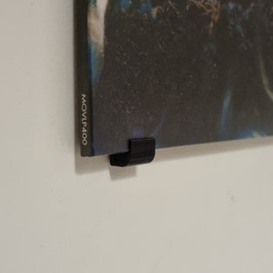 May include: A black vinyl record with a dark blue and green image of a creature with a large mouth. The record is hanging on a wall with a black plastic record holder. The record label reads "MOVLP400".