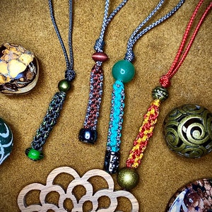 May include: Five colorful beaded keychains with different colored beads and tassels. The keychains are made of braided cord and feature a variety of colors, including red, yellow, green, blue, and black.
