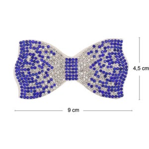 Puede incluir: Una pajarita de pedrería azul y plateada que mide 9 cm de ancho y 4,5 cm de alto.