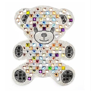Könnte beinhalten: Ein farbenfroher Strass-Teddybär-Applikation. Der Bär besteht aus kleinen, quadratischen Strasssteinen in verschiedenen Farben, darunter klar, rosa, lila, blau, grün und gelb. Die Augen und die Nase des Bären sind schwarze Strasssteine.