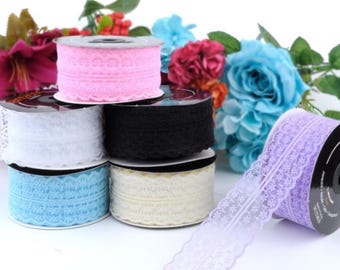 May include: Assortment of six spools of lace trim in various colors, including pink, white, black, light blue, and lavender. The lace trim is delicate and features a scalloped edge.
