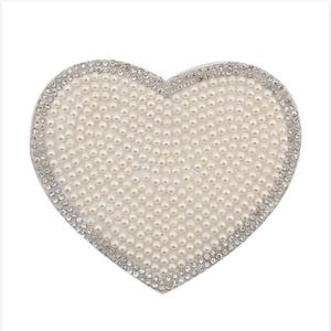 May include: A white heart-shaped clutch purse covered in faux pearls and rhinestones.