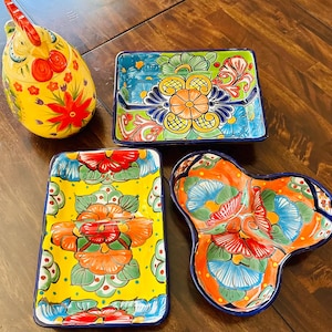 May include: Four colorful ceramic serving dishes with floral designs. The dishes are in shades of blue, green, yellow, orange, and red. The dishes are perfect for serving snacks, dips, or appetizers.