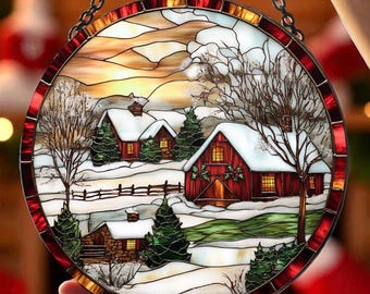 May include: Round stained glass window art depicting a winter scene with snow-covered red barns, trees, and a sunset. The artwork is framed with a red and clear glass border and is held by a silver chain.