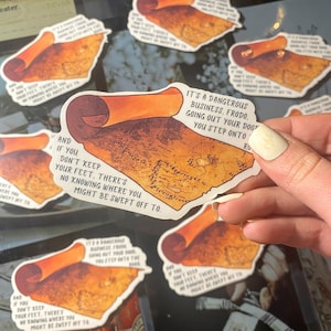 May include: A set of five stickers featuring a hand-drawn illustration of a rolled-up parchment with a map and text. The text reads "It's a dangerous business, Frodo. Going out your door you step onto roads... And if you don't keep your feet, there's no knowing where you might be swept off to."