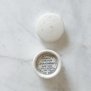 May include: Two small, white, round ceramic containers. One lid is plain, the other has black text that reads "J.B. Thorn Chemist, London, John A. Tarrant, New York, Sole Agent for the United States."