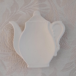May include: White ceramic teapot-shaped dish. The dish is blank and ready to be painted.