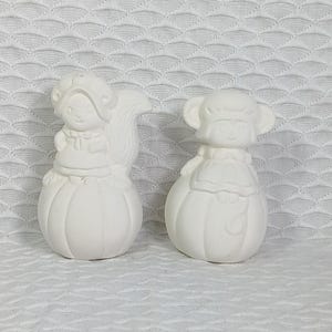 May include: Two white ceramic pumpkin salt and pepper shakers. The salt shaker is shaped like a squirrel wearing a pilgrim hat and the pepper shaker is shaped like a monkey wearing a pilgrim hat.