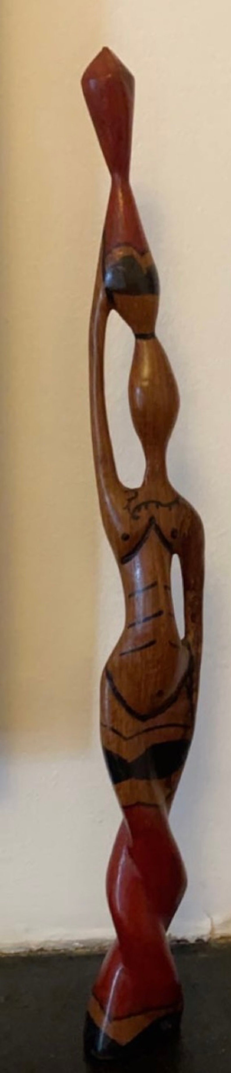Pode incluir: Uma escultura de madeira de uma mulher carregando uma cesta na cabe&ccedil;a. A escultura &eacute; pintada em tons de marrom, vermelho e preto.