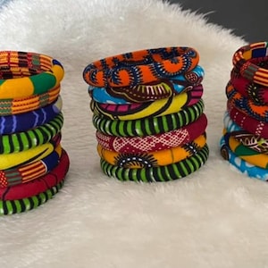 Può includere: Un set di braccialetti in tessuto colorati con motivi a stampa africana. I braccialetti sono realizzati in tessuto intrecciato e sono disponibili in una varietà di colori e design.