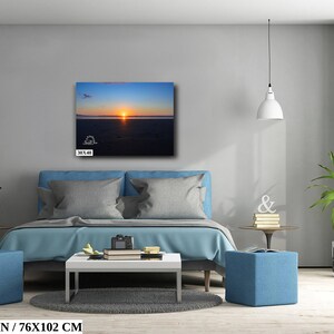Waves form a curtain from horizon to horizon as the sunset creates a spectacular, colorful display of oranges, and yellows as it sets over Playa Tamarindo, Costa Rica. A 30x40 inch print hangs above a bed for perspective.