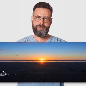 Waves form a curtain from horizon to horizon as the sunset creates a spectacular, colorful display of oranges, and yellows as it sets over Playa Tamarindo, Costa Rica. A man holds a 1x3 foot print for perspective.