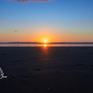 Waves form a curtain from horizon to horizon as the sunset creates a spectacular, colorful display of oranges, and yellows as it sets over Playa Tamarindo, Costa Rica. This wall art is available in glossy photo prints, or canvas.