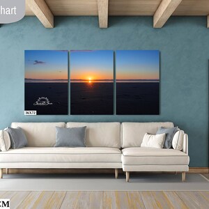 Waves form a curtain from horizon to horizon as the sunset creates a spectacular, colorful display of oranges, and yellows as it sets over Playa Tamarindo, Costa Rica. A 36x72 inch print hangs above a sectional sofa for perspective.