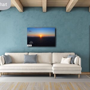 Waves form a curtain from horizon to horizon as the sunset creates a spectacular, colorful display of oranges, and yellows as it sets over Playa Tamarindo, Costa Rica. A 24x36 inch print hangs above a sectional sofa for perspective.