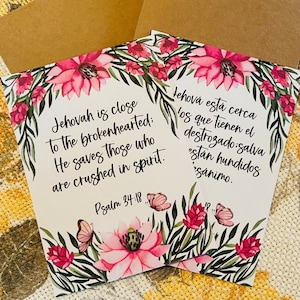 May include: Two floral cards with a white background and pink flowers. The text on the cards reads "Jehovah is close to the brokenhearted: He saves those who are crushed in spirit. Psalm 34:18" and "Jehová está cerca los que tienen el destrozado: salva están hundidos sánimo."