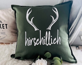 May include: A green throw pillow with white antlers and the text "hirschchillig" in white.