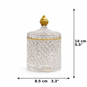 K&ouml;nnte beinhalten: Ein klares Glasgef&auml;&szlig; mit Rautenmuster, einem goldenen Rand und einer goldenen Spitze auf dem Deckel. Das Gef&auml;&szlig; ist 14 cm hoch und 8,5 cm breit. F&uuml;r dekorative Zwecke.