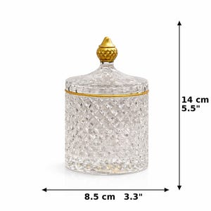 May include: A clear glass jar with a diamond pattern, a gold rim, and a gold finial on the lid. The jar is 14 cm tall and 8.5 cm wide. The jar is designed for decorative use.