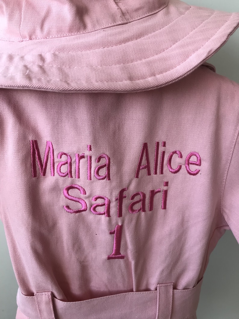 K&ouml;nnte beinhalten: Rosa Safari-Jacke mit gesticktem Text "Maria Alice Safari 1" auf der R&uuml;ckseite.