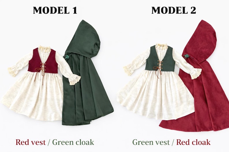 May include: Two doll-sized outfits are displayed, each featuring a dress, vest, and cloak. One outfit has a red vest and a green cloak, while the other has a green vest and a red cloak. The dresses are white with long sleeves and lace trim.